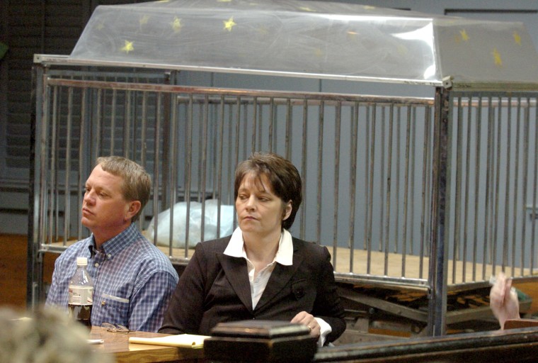 Tom and Debra Schmitz wait as the lawyers have a sidebar with Judge Clayburn Peeples during the first day of their child abuse trial in Brownsville, Tenn., Monday, Jan. 30, 2006. The Schmitzes sit in front of what was called \"the cage,\" a covered bed that was sometimes used for punishment, according to one of the children living in their house at the time of the alleged incidents. (AP Photo/The Jackson Sun, Helen Comer)